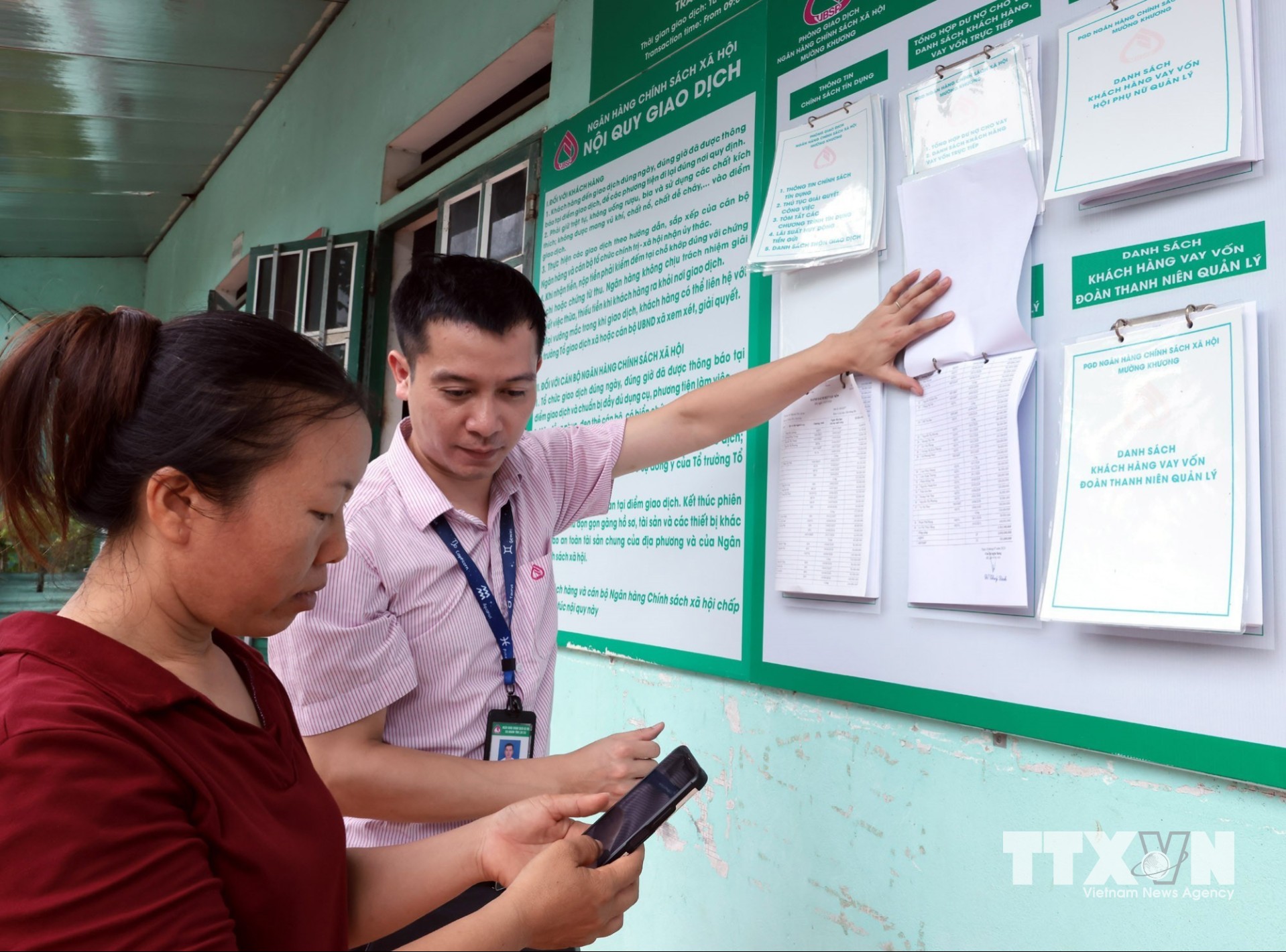 Tổ trưởng Tổ Tiết kiệm và vay vốn đối chiếu danh sách hộ vay được số hóa với danh sách niêm yết công khai tại điểm giao dịch xã Bản Lầu, Lào Cai. (Ảnh: Trần Việt/TTXVN)